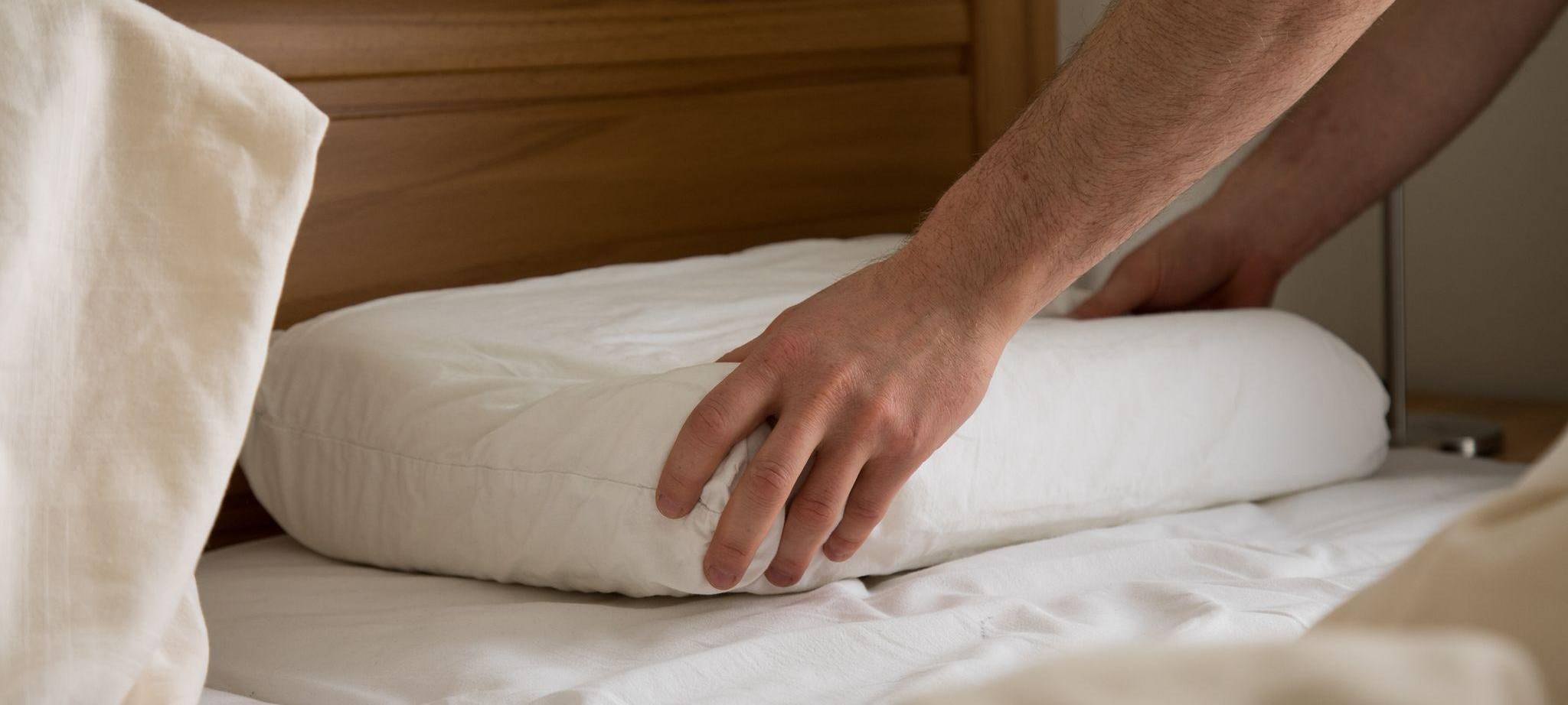 Eine Person greift nach einem flachen Kopfkissen