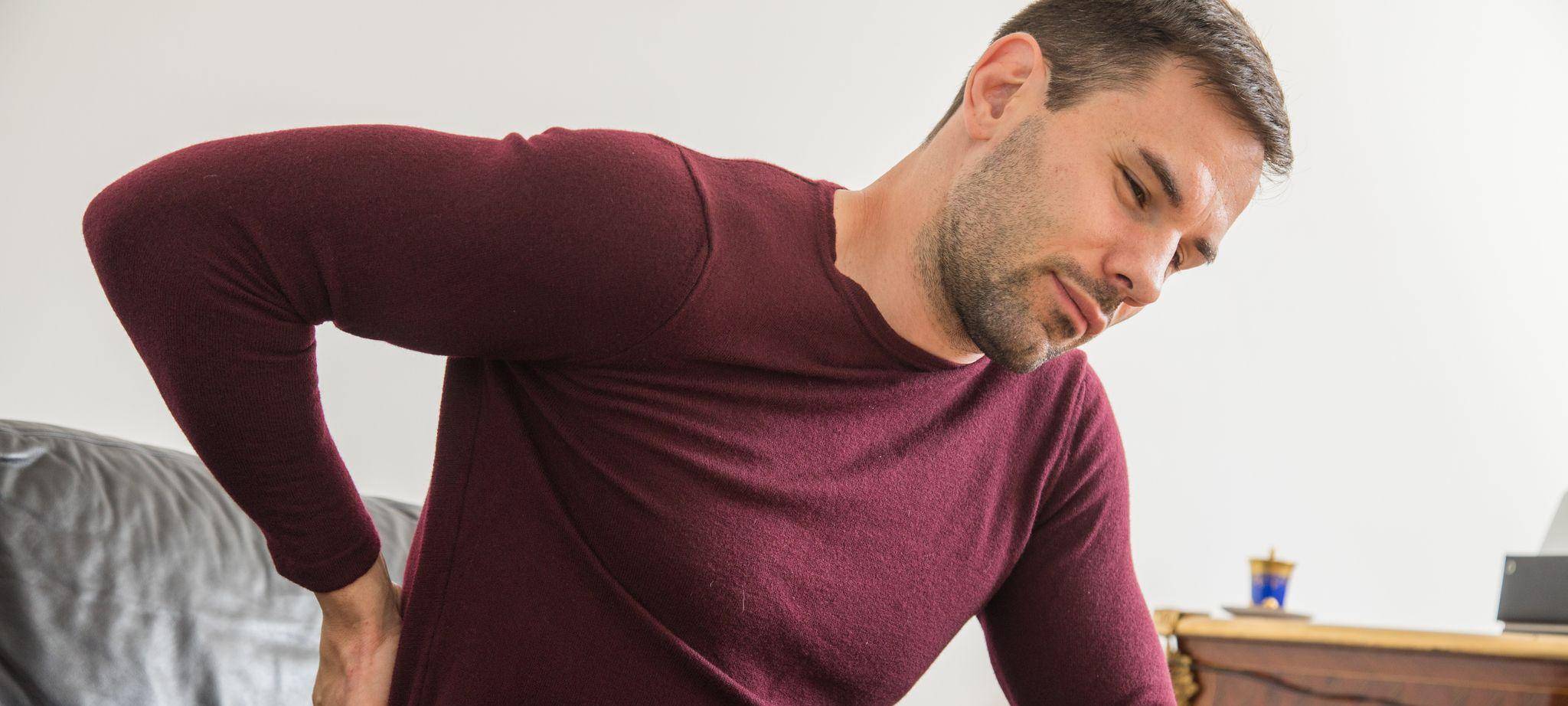 Ein Mann hält sich den unteren Rücken